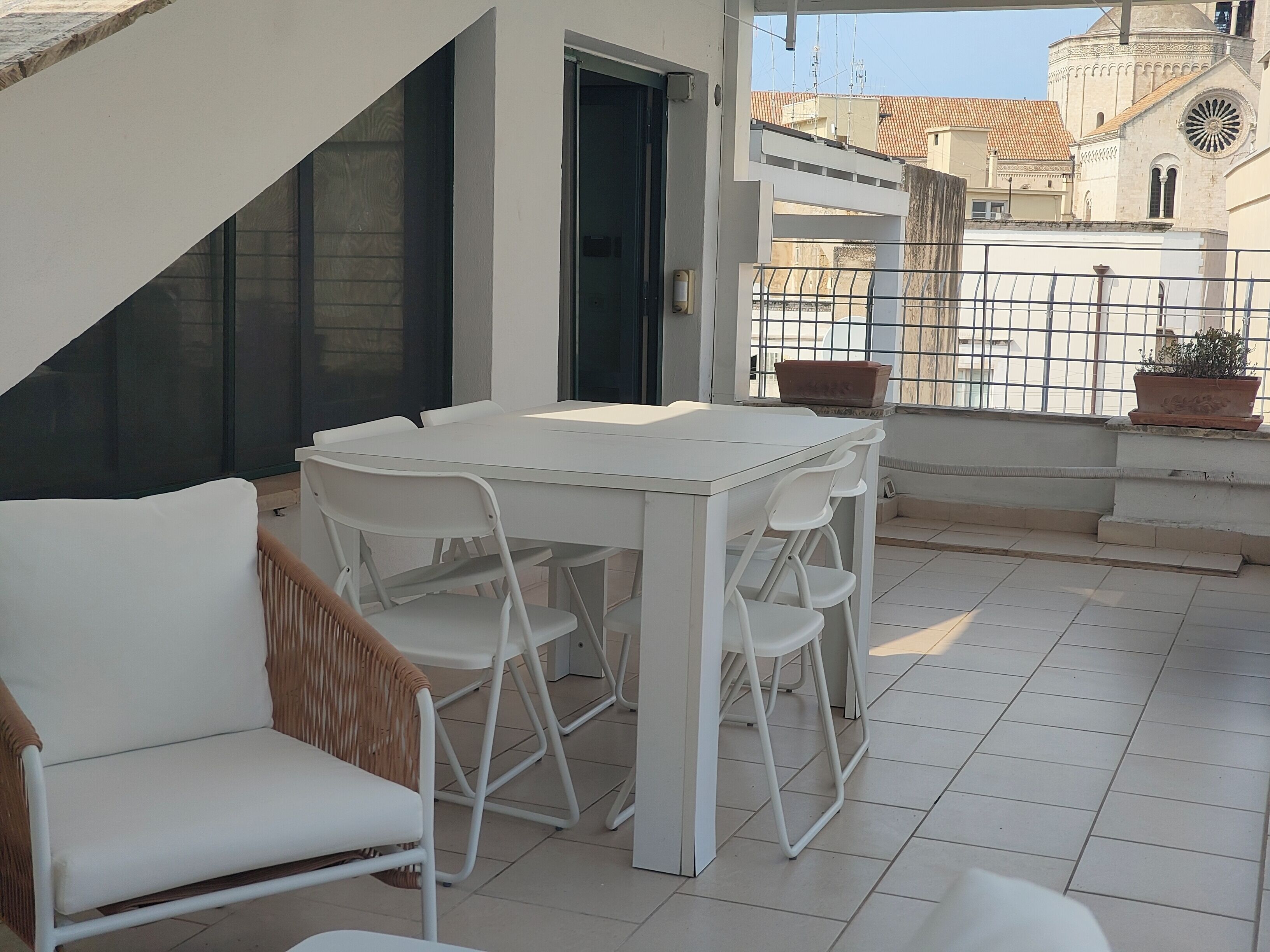 Un tavolo e delle sedie bianche su un balcone, con vista su un edificio con una cupola e un campanile.