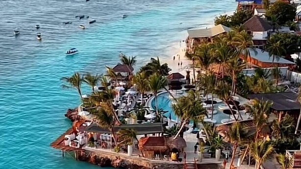 A coastal resort with a beach, swimming area, and several buildings with balconies overlooking the sea. - Green House Zanzibar (Nungwi)