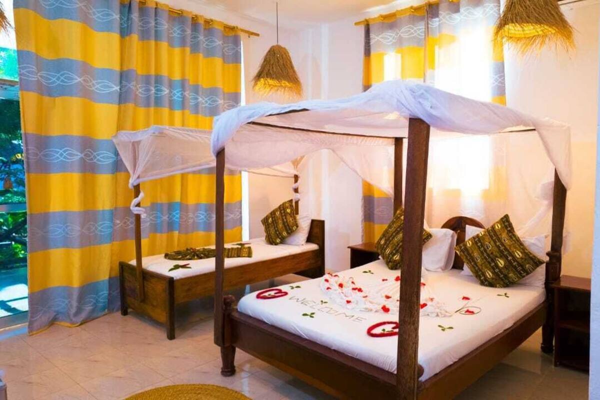 Una cama con dosel, dos mesitas de noche y un cojín decorativo.