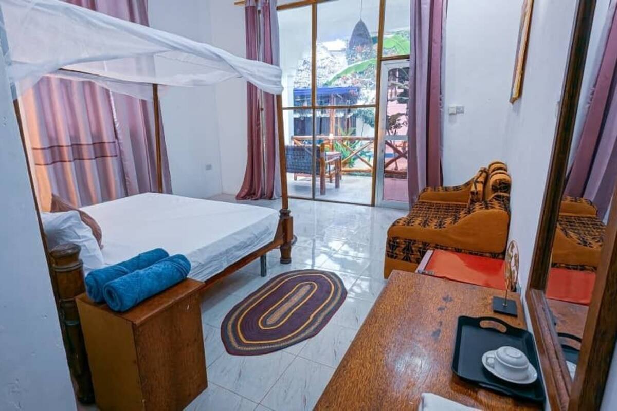 Un dormitorio con cama, mesita de noche, una silla y vistas al exterior.