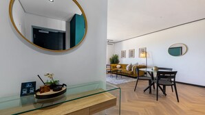 A modern living room with a glass coffee table, a round mirror, and a sofa.
