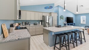 Una cocina moderna con encimeras de granito, electrodomésticos de acero inoxidable y una isla grande con taburetes de bar.