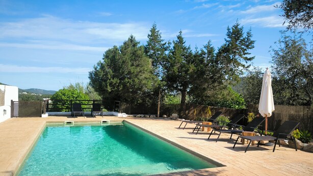 A rectangular swimming pool with a wooden deck and lounge chairs.