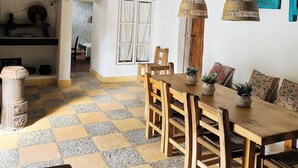A rustic dining area with a checkered floor, wooden furniture, and a high ceiling with exposed beams.