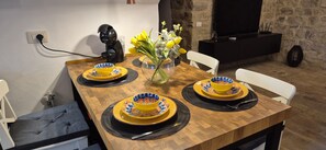 Ein Esstisch, gedeckt mit gelben Schüsseln und Tellern, eine Kaffeemaschine und eine Vase mit Blumen.