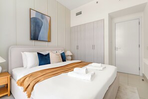 Een moderne hotelkamer met een groot bed, een kledingkast en een schilderij aan de muur.