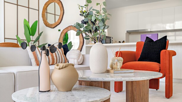 Un salon moderne avec une table basse ronde en bois, un vase beige et une plante en pot.