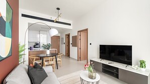 Un salon moderne comprenant un canapé, un téléviseur et un coin repas avec une table et des chaises.
