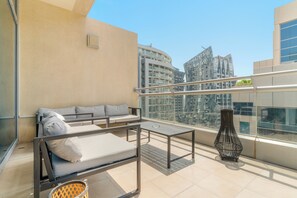A balcony with a sofa, a table, and a decorative vase. - Silkhaus Bay Square 13 (Dubai)