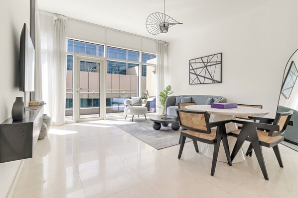 A modern living room with a dining area, large windows, and a view of the cityscape. - Silkhaus Bay Square 13 (Dubai)