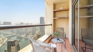 A balcony with a view of a cityscape and river, furnished with two chairs and a small table with a plant. - Silkhaus Amwaj 4 (Dubai)