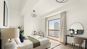 A modern bedroom with a large bed, a desk, and a view of the city. - Silkhaus Amwaj 4 (Dubai)
