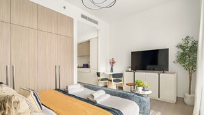 Une chambre d’hôtel moderne avec un grand lit, une télévision, un bureau et une plante en pot.