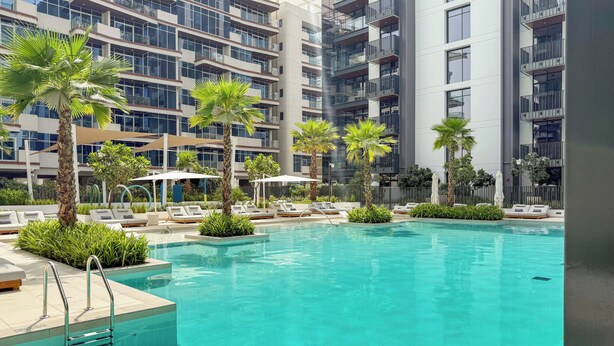 Un hôtel moderne doté d’une piscine, de palmiers et de chaises longues.