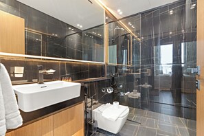 A modern bathroom with a large mirror, a white sink, and a glass-enclosed shower area.