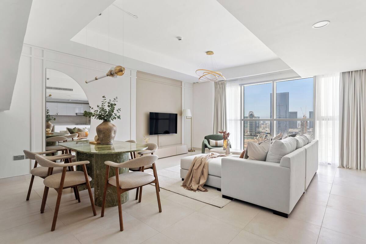 A modern living room with a dining area, a sofa, and a TV.