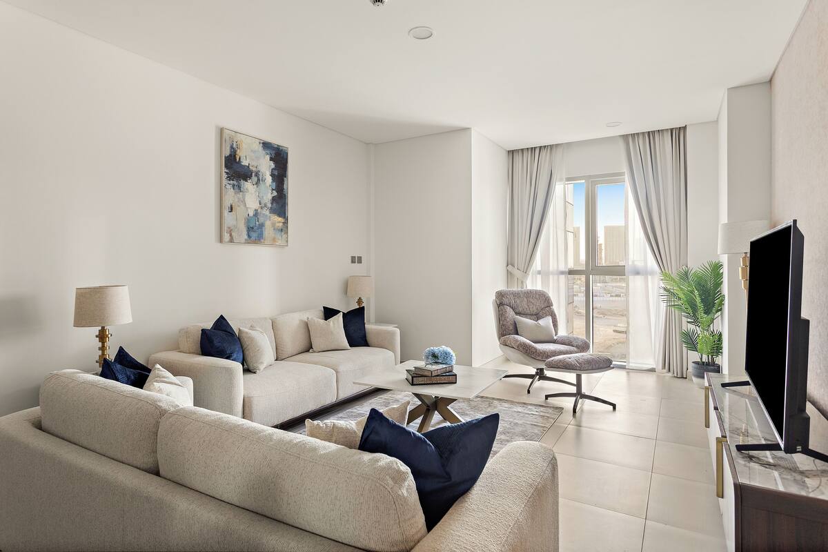 A modern living room with a sofa set, a coffee table, a TV, and a view of the outdoors.