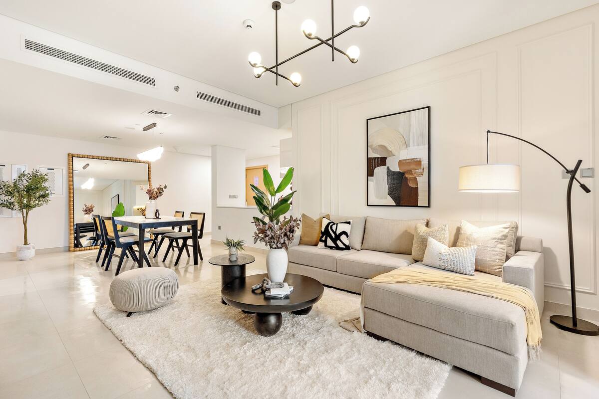 A spacious living room with a modern sofa, a coffee table, and a dining area with a table and chairs.