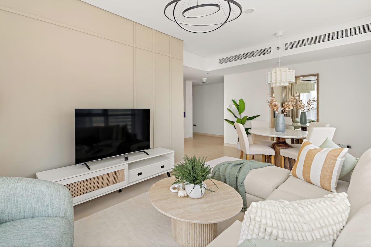A modern living room with a flat-screen TV, a round coffee table, and a sofa.