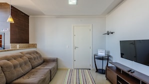 Un salon avec un canapé, un téléviseur, une petite table et une porte.