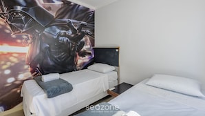 Une chambre d’hôtel avec deux lits, une grande fresque murale représentant un personnage et un lit avec un oreiller gris.