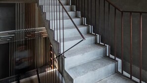 Un escalier avec un mur en béton et des rampes en métal, menant à un niveau supérieur.