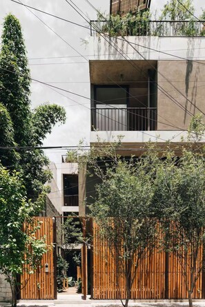 Un bâtiment moderne avec une façade en béton, des clôtures en bois et de la verdure.