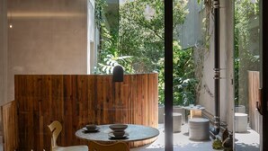 Un espace repas moderne avec une table ronde, deux chaises et un séparateur en bois.
