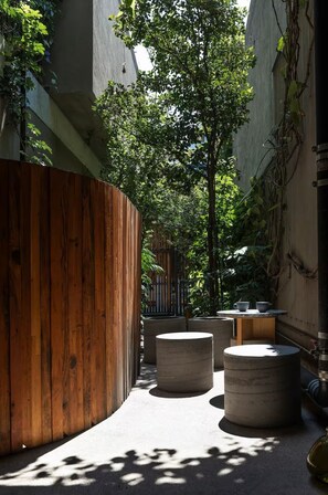 Une cour avec des bancs en bois, une table en béton et un porte-vélo en métal.