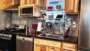 A modern kitchen with wooden cabinets, stainless steel appliances, and a window providing natural light.