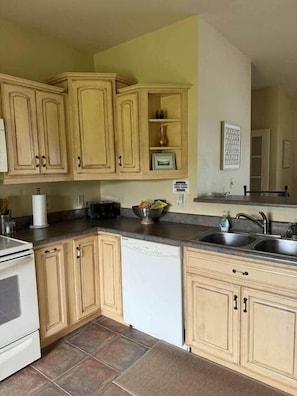 A kitchen with wooden cabinets, a dishwasher, a sink, and a countertop with various items.