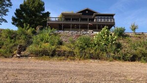 A two-story house with a balcony, surrounded by dense vegetation and a clear sky. - T&E Riverhouse Retreat (Hanover)