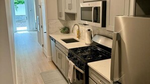 Una cocina moderna con electrodomésticos de acero inoxidable, suelo de madera clara y armarios blancos.