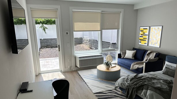 Un dormitorio moderno con cama, escritorio, silla, mesita de centro y televisor.