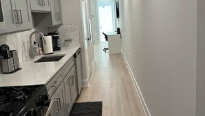 Une cuisine moderne avec des meubles gris, une cuisinière noire et un tapis noir.