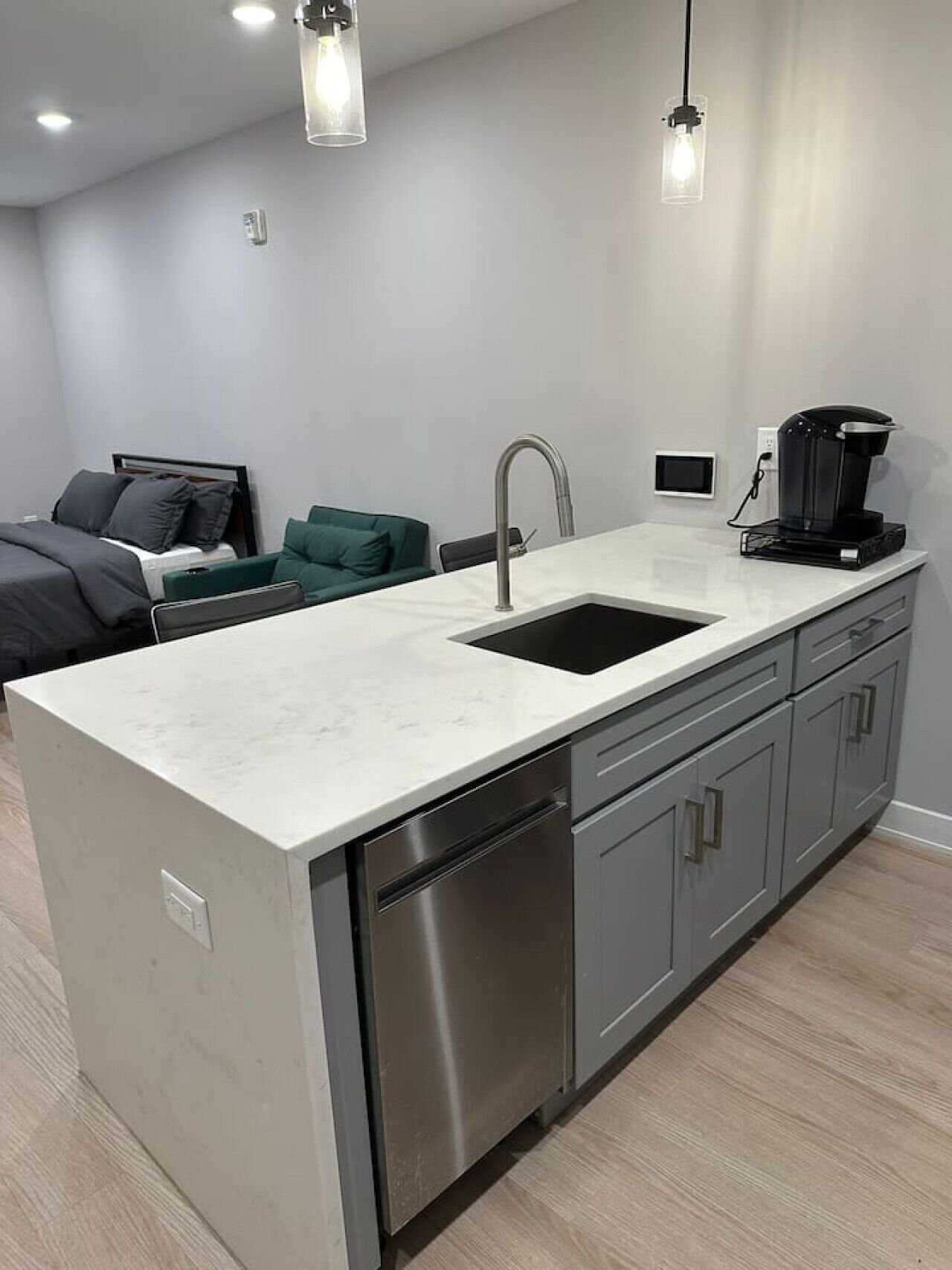 A modern kitchen with a white countertop, stainless steel appliances, and a coffee maker.