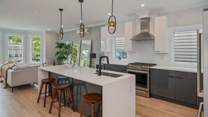 Una cocina moderna con una isla central, taburetes de bar y un ventanal con vistas al exterior.