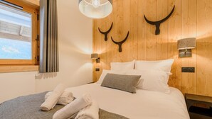 A bedroom with a wooden headboard, two wall-mounted lights, a window with curtains, and a bed with white linens and rolled towels. - Wifi, 300m from resort center, balcony, parking, tv, ski locker, 39-46m², Champagny-en-Vanoise (Champagny-en-Vanoise)