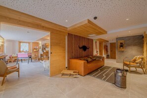 Amplia sala de estar con un sofá de madera, una mesa de comedor y una cocina al fondo.