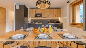 Una cucina moderna con mobili in legno, un'isola centrale e un'area pranzo per sei persone, con un tavolo grande e sedie.
