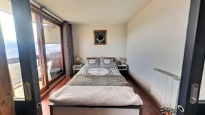 Un dormitorio con cama, mesita de noche, lámpara y ventana con vistas.