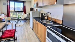 A compact kitchen with wooden cabinets, a black countertop, a stainless steel sink, and a stove.