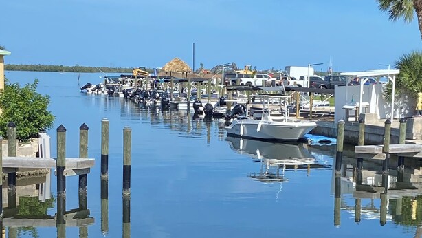 A marina with boats docked, wooden pilings, and a calm water surface.