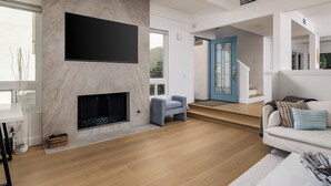 A modern living room with a fireplace, a flat-screen TV, a sofa, and a staircase leading to another level. - Walk to the BEACH from this Monarch Bay Villa in Dana Point!! (Dana Point)