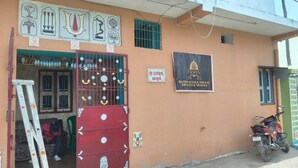 A building with a sign reading "Brahma Dhami Bhakta Nivas" and a red gate with decorative elements.