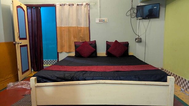 A room with a bed, a television, and a door.