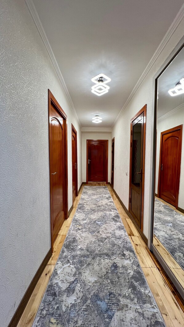 A hallway with wooden doors, a patterned carpet, and a ceiling light fixture.