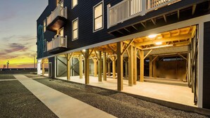 A two-story building with a balcony on the second floor, large windows, and a covered outdoor area with wooden beams.