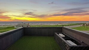 Eine Dachterrasse mit Blick auf den Sonnenuntergang über dem Meer.