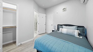 A bedroom with a bed, a nightstand, a wardrobe, and a door leading to a bathroom.